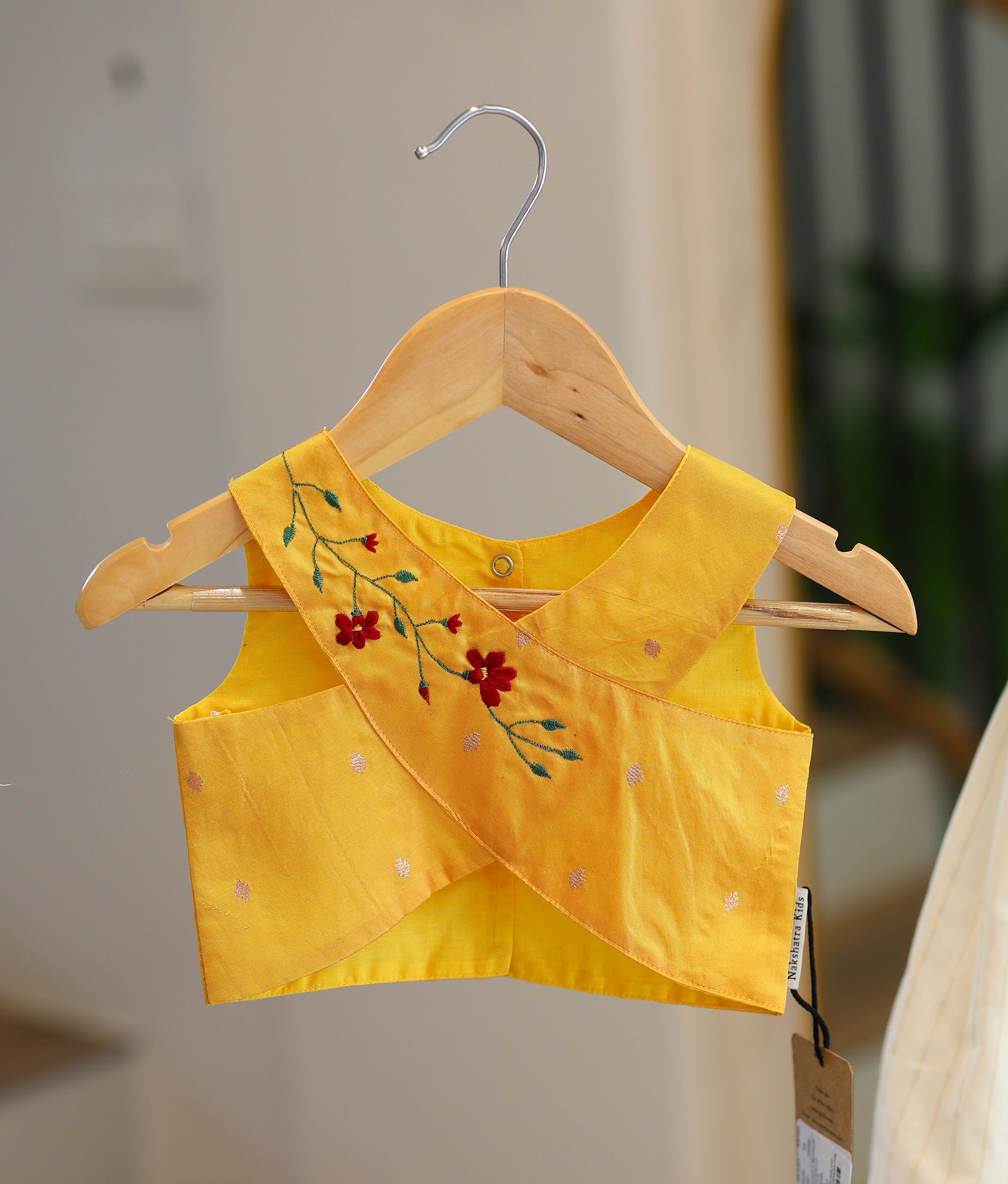 Close-up of the yellow top showing the crossover pattern and the red floral embroidery.