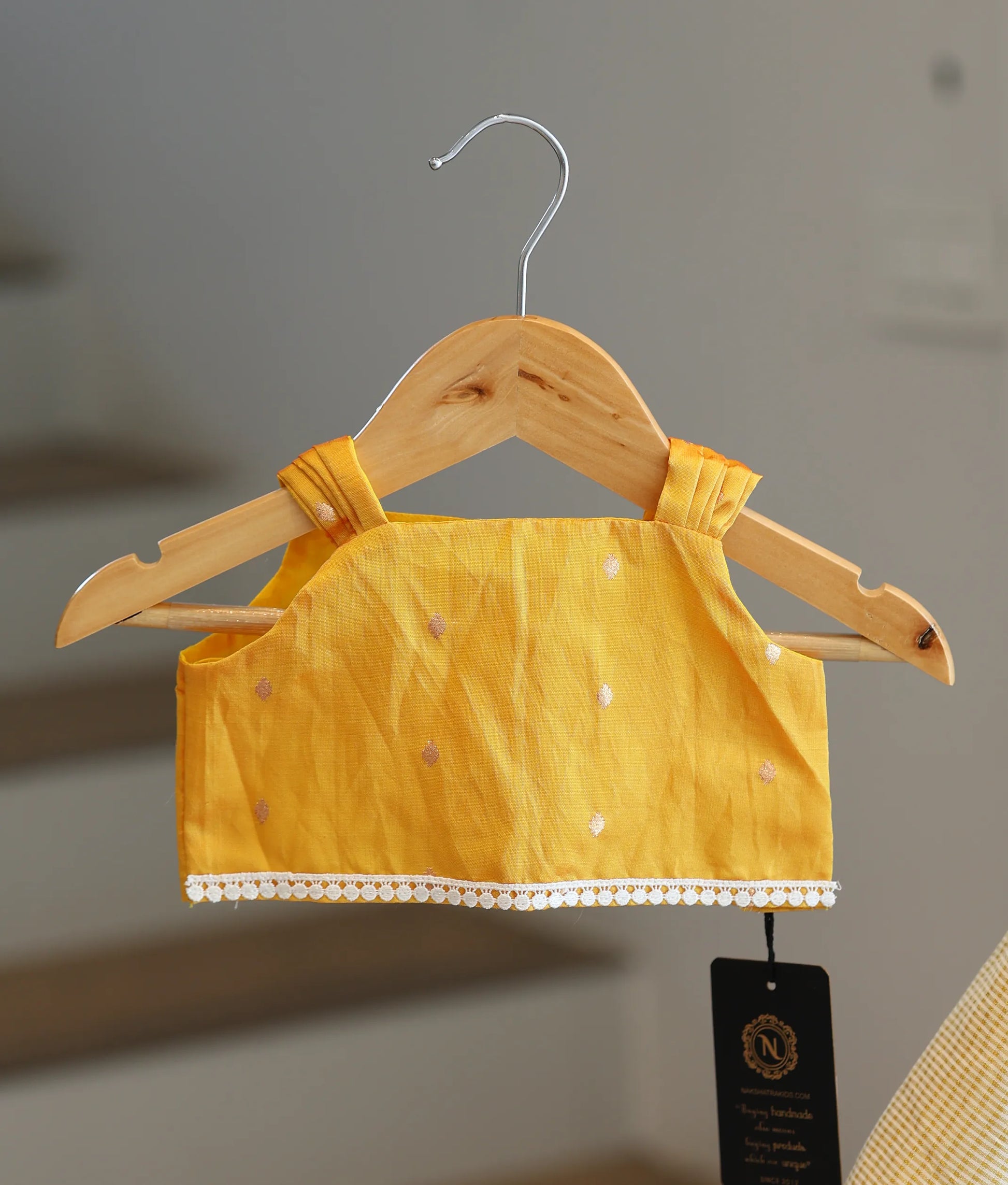 Close-up of the yellow top showing the pleated shoulder straps and white lace hem detailing.