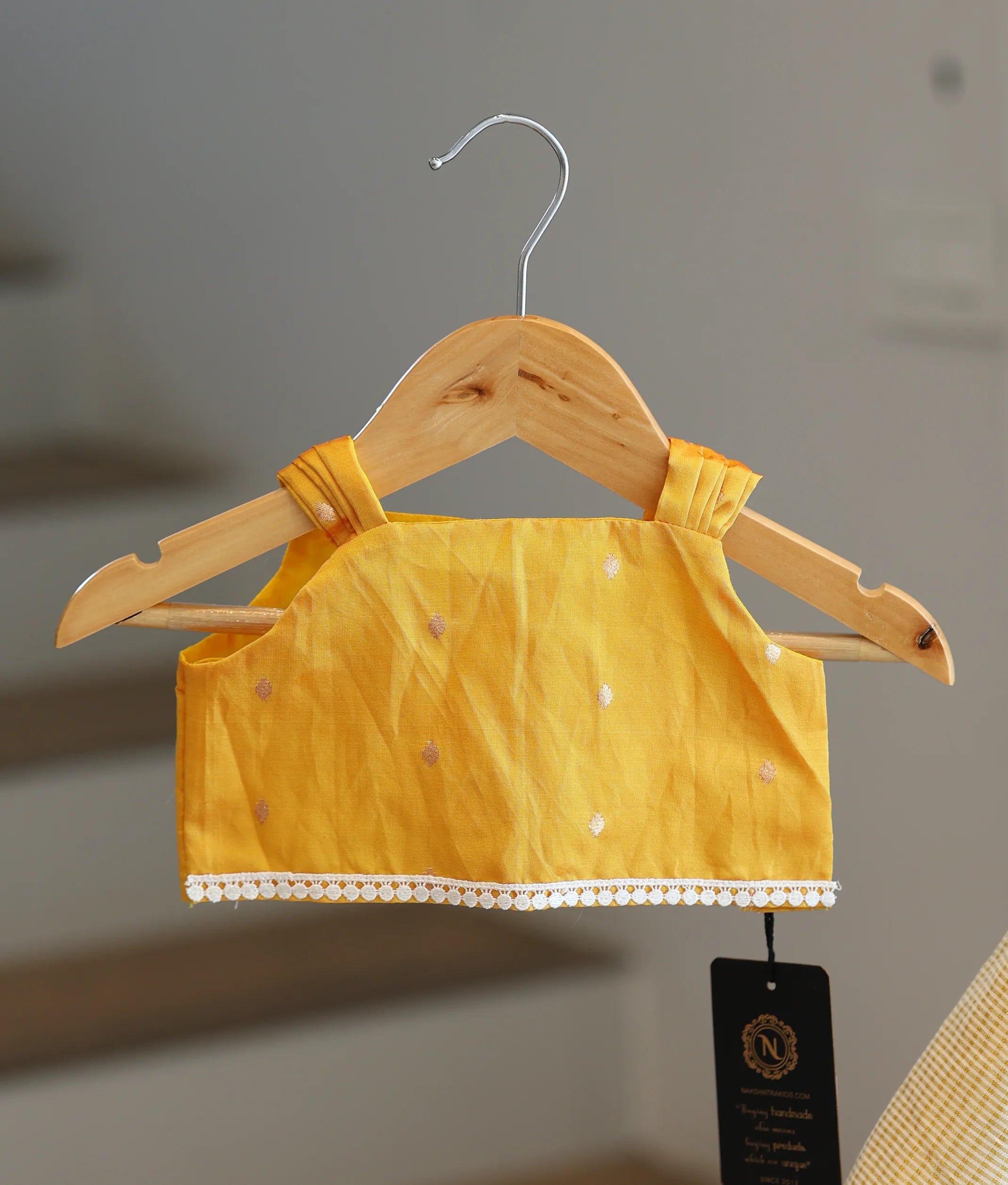 Close-up of the yellow top showing the pleated shoulder straps and white lace hem detailing.