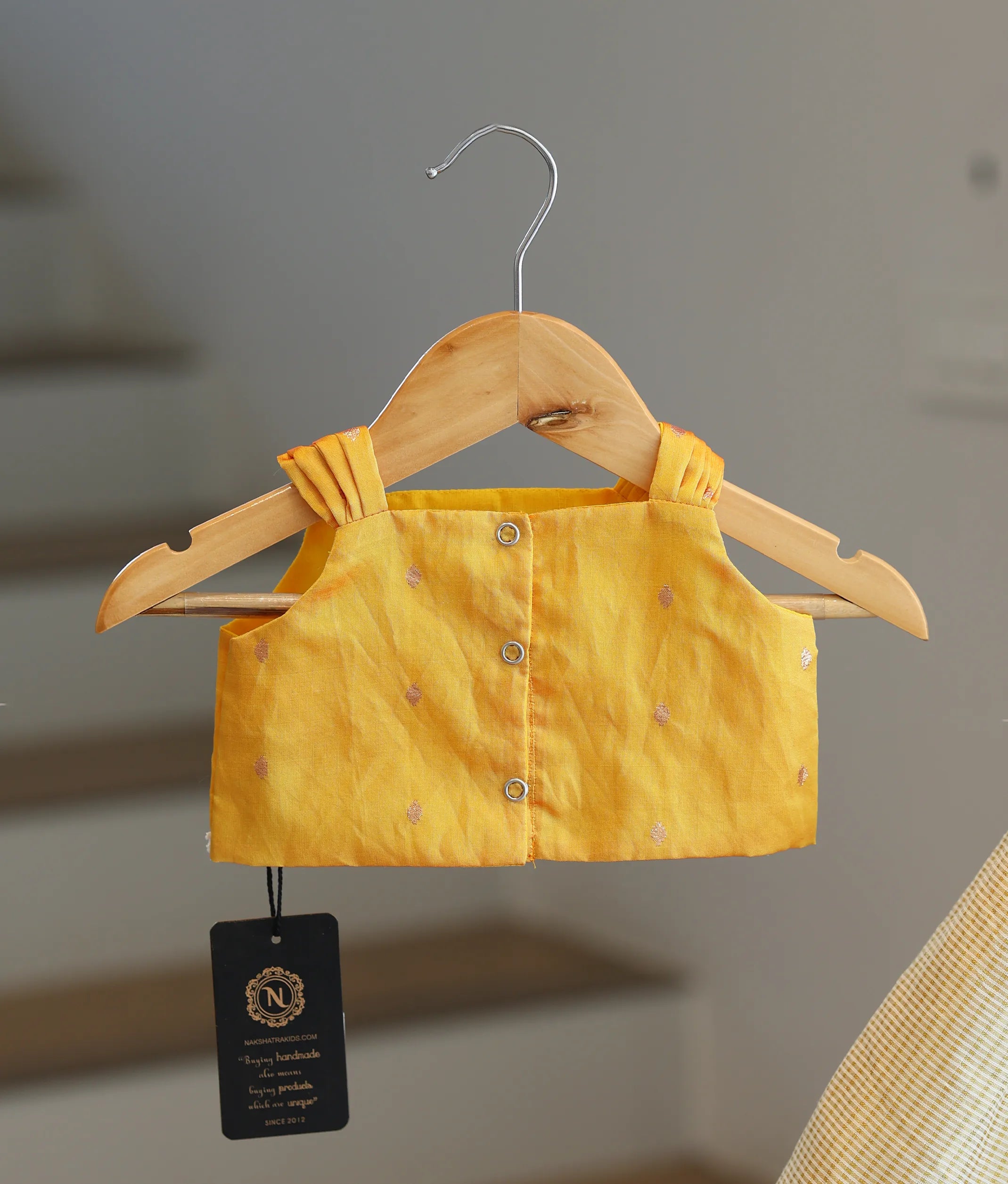 Back view of the yellow top showing the row of secure button closures and clean finish.